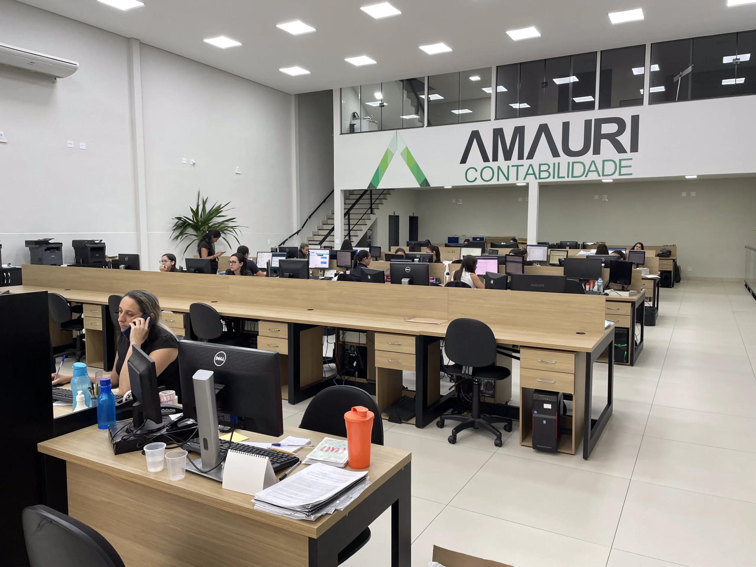 Equipe da Amauri Contabilidade trabalhando no escritório, com o letreiro da empresa ao fundo